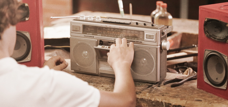 boy puts tape in old radio red speakers